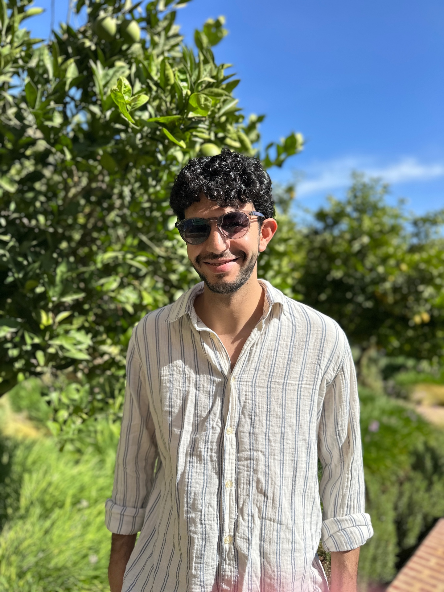 Moha, the local host of Morocco by Heart, smiling in a sunlit citrus garden in Morocco